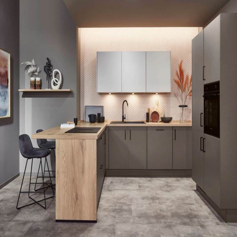 Exklusive U-Küche mit Holztresen – Küchenstudio Regensburg Exklusive U-Küche in Grau mit Tresen aus Holz, Barhockern und indirekter Beleuchtung