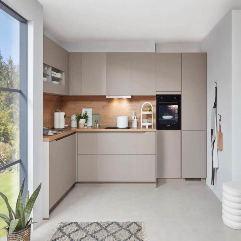 Musterküche in Kaschmir Musterküche in Kaschmir als L-Küche mit Holzrückwand und Backofen im Hochschrank – Küchenstudio Regensburg